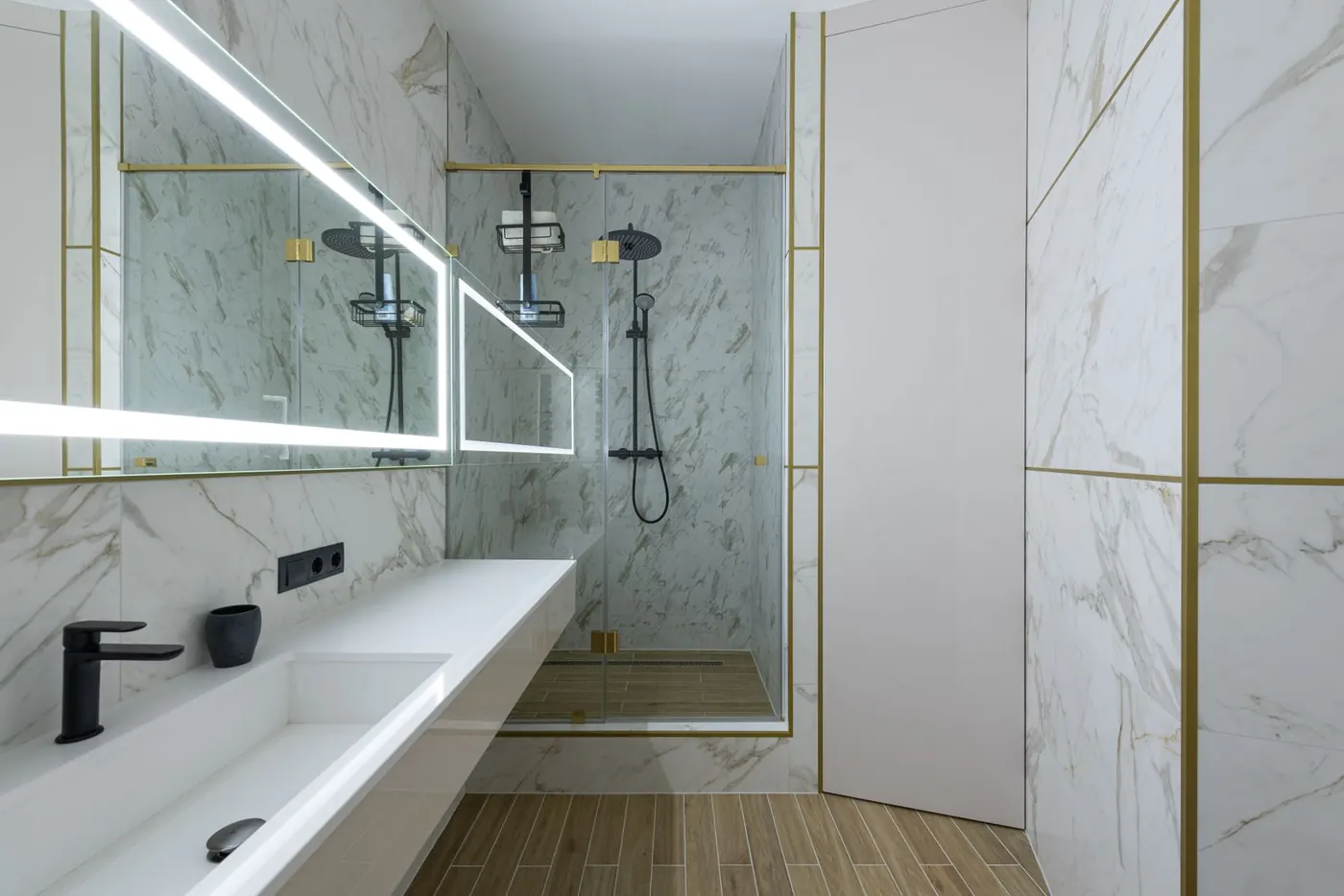 Walk-in shower with marble-look tile and a lit mirror over a floating vanity